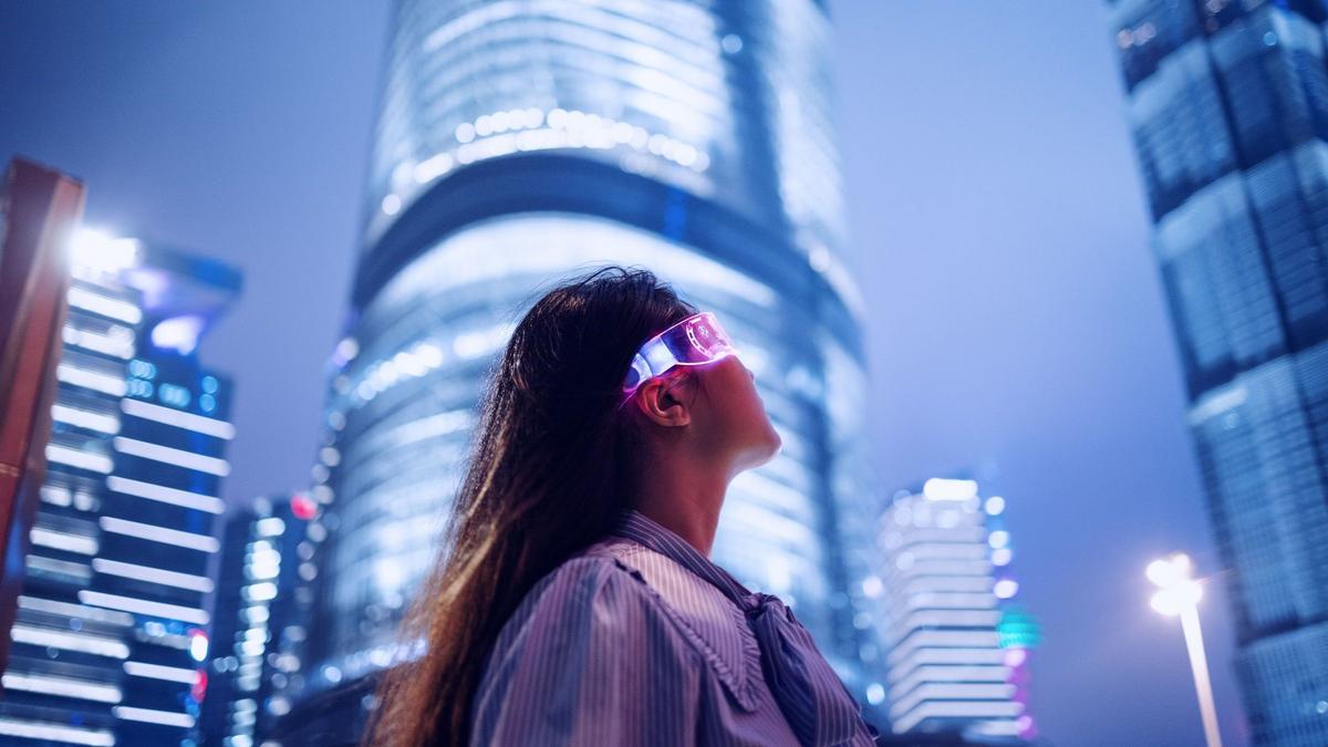 Woman wearing futuristic glasses looking up at a modern city skyscraper
