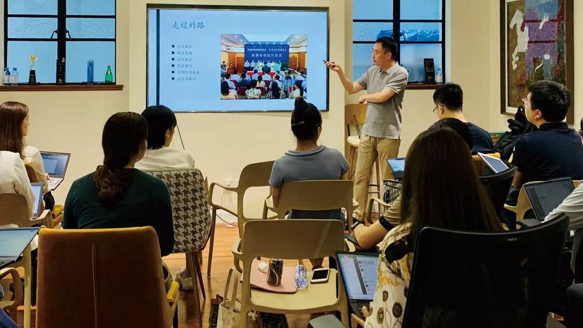 Cui Wei giving a presentation about artificial intelligence to an audience in a conference room with a digital screen.