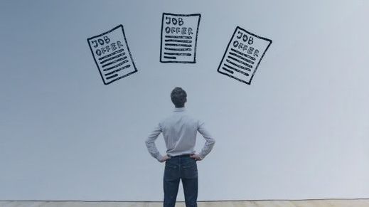 Professional looking at three hand-drawn job offer documents on a wall