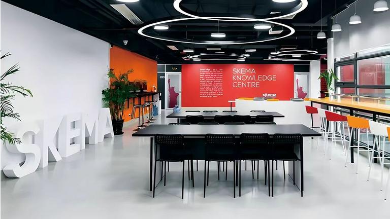 Interior of the modern SKEMA Knowledge Centre featuring collaborative desks, seating areas, and a red branded wall.