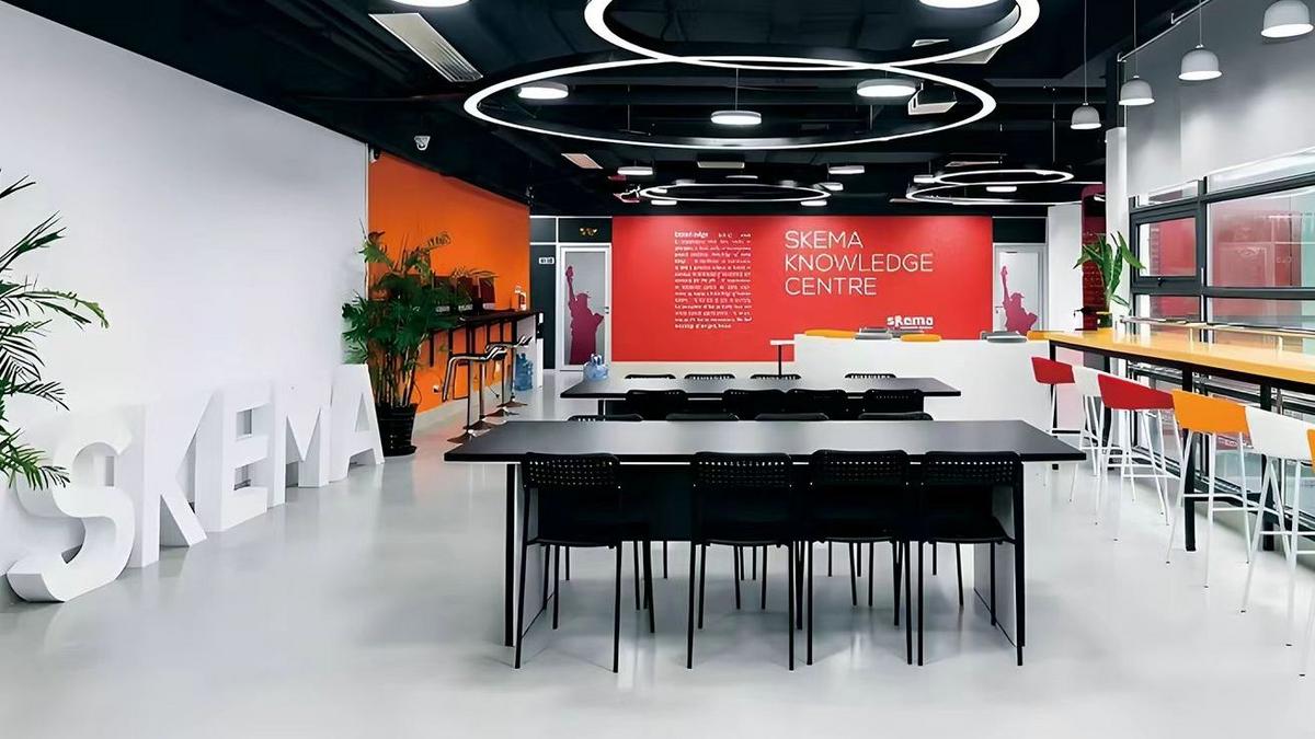 Interior of the modern SKEMA Knowledge Centre featuring collaborative desks, seating areas, and a red branded wall.